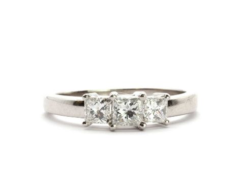 A platinum three stone diamond ring,a princess cut diamond four claw set to the centre, a smaller princess cut diamond claw s