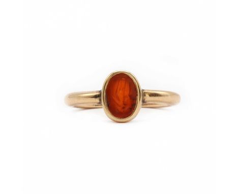 A gold and hardstone intaglio ring,set with an oval flat top cornelian, carved with a man possibly holding a spear and a shie