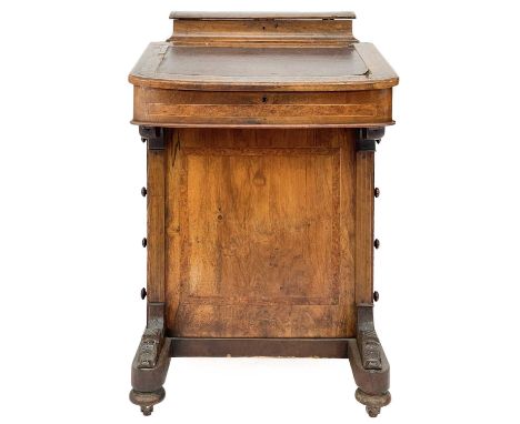 A Victorian walnut Davenport. The writing slope lifts to reveal an arrangement of compartments with four short drawers on cer