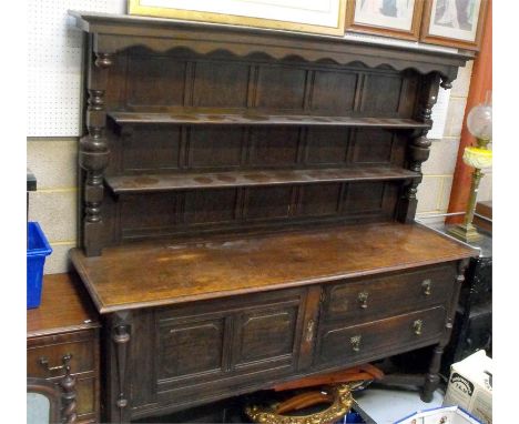 An oak dresser, with two shelf plate rack above two long drawers and a cupboard, on turned legs joined by a stretcher, 181cm.