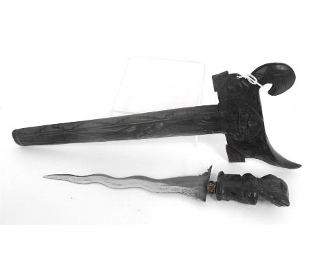 An Indonesian Kris with carved handle and scabbard and having a steel blade, overall length 38cm (blade length 18.5cm) 