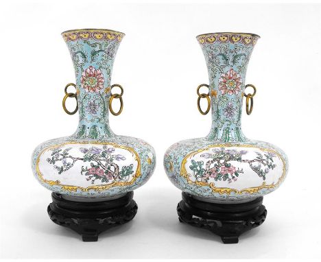 A pair of Chinese enamel vases on stands, decorated with flowers on a pale green ground, 20cm high.