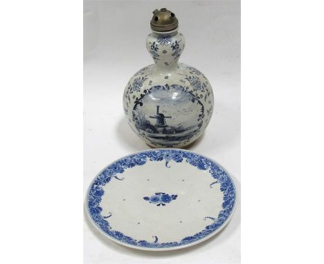 A Dutch Delft lamp base, decorated a windmill a boat and flowers 32cm high and a Delft plate 29cm diameter (2)