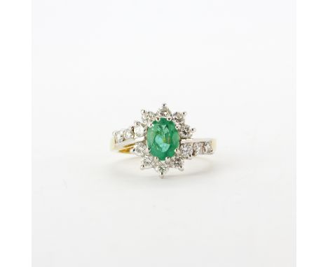 An 18ct yellow and white gold ring set with an oval cut emerald and brilliant cut diamonds, approx. 1.2ct overall, (N.5).