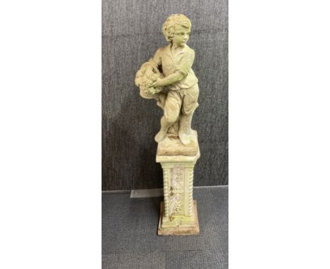 A concrete garden figure of a boy carrying a basket of fruit on a concrete plinth, overall H. 132cm.