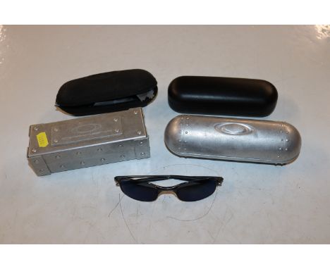 A pair of Oakley sunglasses and four various Oakley glasses cases