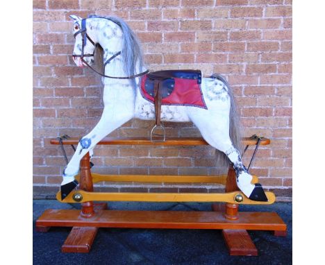 A CARVED WOOD ROCKING HORSE  the side glancing head with inset glass eyes, flared nostrils and an open mouth with teeth, the 
