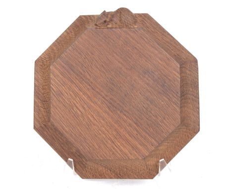 A Robert 'Mouseman' Thompson carved oak cheese board The stained oak board of octagonal form, carved to the exterior side wit
