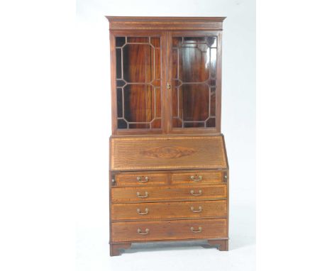 An Edwardian inlaid mahogany bureau bookcaseWith a dentil cornice above a crossbanded frieze over two astragal glazed doors e