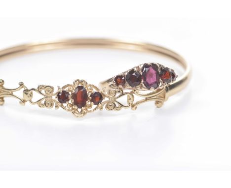 A 9k gold and garnet set bangleCentering oval shape garnets to a scroll surround, together with, a garnet five stone ring, mo