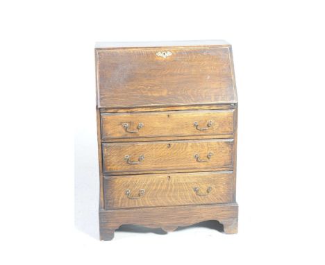 An oak Georgian style bureau, 20th Century With fallfront above three graduated drawers and shaped apron, raised on bracket f