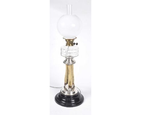 An unusual early 20th Century taxidermy oil lamp, (converted to electricity)The spreading circular ebonised base extending to