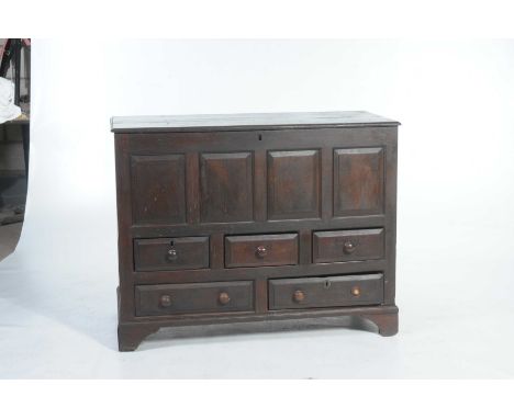 An 18th Century oak mule chestThe rectangular moulded plank top above four panels and an arrangement of five short drawers ea