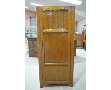 A 1930's oak hall robeThe single door enclosing hanging space and a single shelf, raised upon block feet, 76x176x42cm.