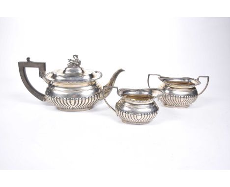 An Edwardian three-piece silver tea service Comprising teapot, twin handled sugar bowl, and single milk jug, with fluted desi