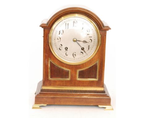 An Edwardian mahogany and brass mounted arch top bracket clock with eight day movement striking on a gong on stepped base and