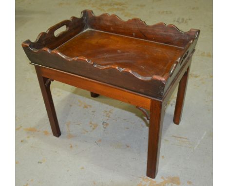 An early 20th Century mahogany tray top serving table in the Chippendale style, with pierced grip handles over block chamfere