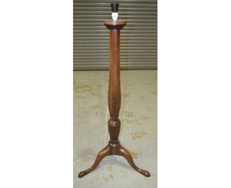 A mahogany standard lamp with foliate carving above a vas shaped column,  with three outswept legs, height excluding the fitt