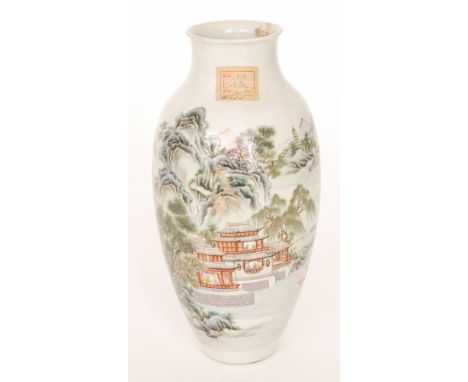 An early 20th Century Chinese vase decorated with a Chinoiserie landscape depicting a temple building within mountains, bears