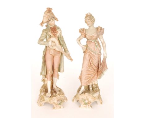 A pair of early 20th Century Royal Dux Bohemia figures of a lady and gentleman, she wearing a pink dress holding her skirt al