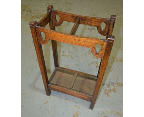 An Arts and Crafts oak twin section umbrella or stick stand, with pierced corner spandrels, complete with drip tray, height 7