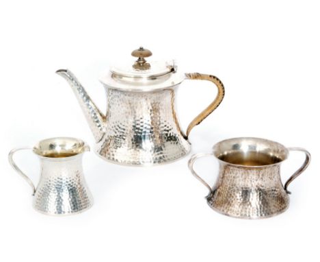 An Arts and Crafts EPBM three piece tea set of beaten waisted form the pot with wicker bound handle and button finial, Joseph