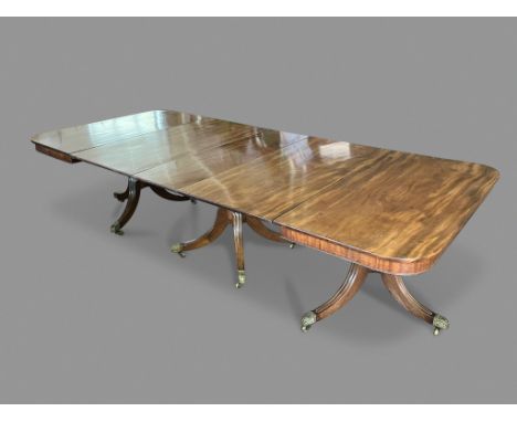 A LATE REGENCY MAHOGANY EXTENDING DINING TABLE, the rounded rectangular top on three turned and outswept pillars, with three 