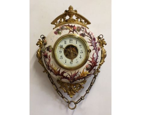 A CONTINENTAL ART POTTERY AND GILT METAL MOUNTED WALL CLOCK, the 5 1/2" cream dial with Arabic numerals and skeletonised cent
