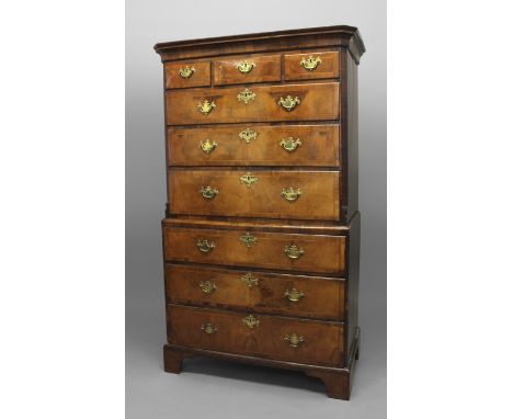 AN 18TH CENTURY WALNUT CHEST ON STAND, the top section with an arrangement of feather-banded drawers flanked by canted, flute