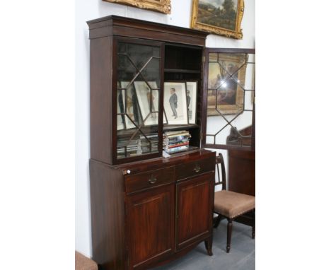 A George III mahogany bookcase cabinet, with astragal glazed doors over two drawers and panel cupboard, standing on shaped sw