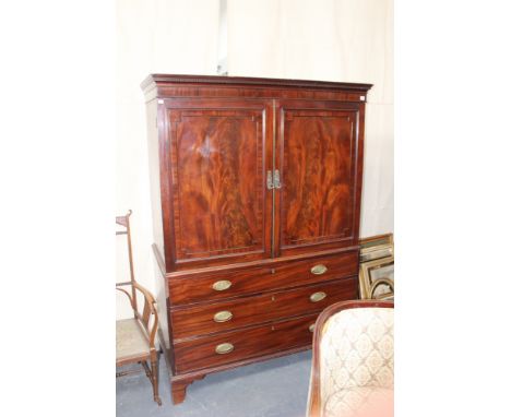 A late Georgian mahogany linen press, the moulded cornice over two panel doors enclosing slides, above three long graduated d