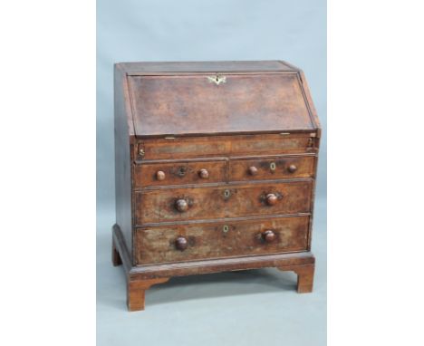An 18th Century walnut and crossbanded bureau of small proportions, the fall front revealing stepped fitted interior with wel