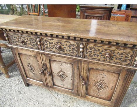 C17 style oak dresser with three blind fret carved drawers above three lozenge carved panel doors with turned wooden handles 