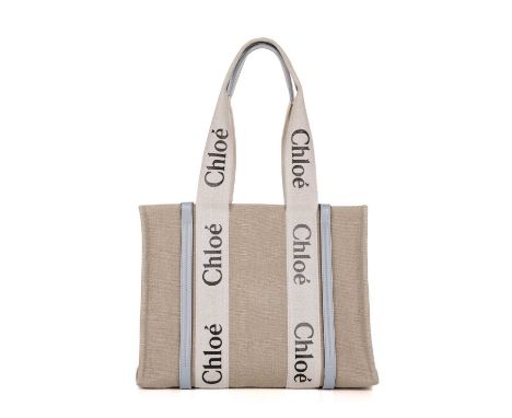Chloe, a Medium Woody tote, designed with a grey canvas exterior and light blue leather trim, featuring logo branded wraparou