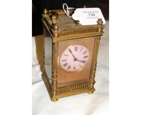 An antique brass cased and enamel carriage clock with repeater mechanism - 13cms high, having 4.5cm diameter pink enamel dial