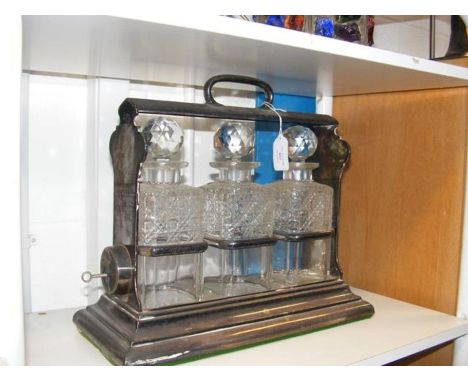 A silver plated tantalus with three glass decanters bearing silver drink plaques 