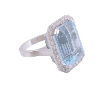  An aquamarine and diamond ring,   the rectangular shaped aquamarine in a four claw setting within a surround of brilliant cu