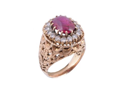  A ruby and diamond cluster dress ring,   the oval cabochon ruby within a surround of brilliant cut diamonds, approximately 0
