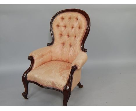 A Victorian mahogany balloon back armchair, with button back and overstuffed floral upholstery, raised on cabriole legs, on c