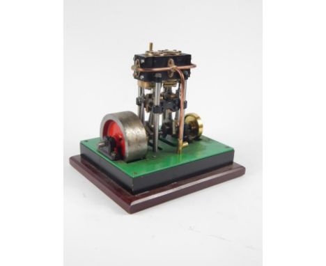 A partial horsepower live steam table top metal engine, with 8cm dia. drive wheel, brass fittings and articulated pistons, on