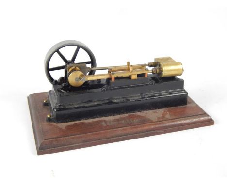 A fractional horse power live steam workshop engine, with articulated brass pieces, 7cm dia. drive wheel on a mahogany base, 