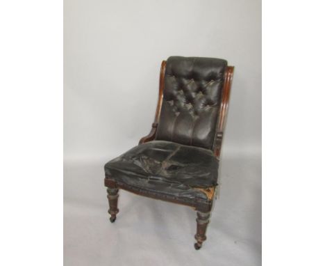 A Victorian mahogany lady's armchair, with button leather back and over stuffed seat, raised on turned legs on castors.