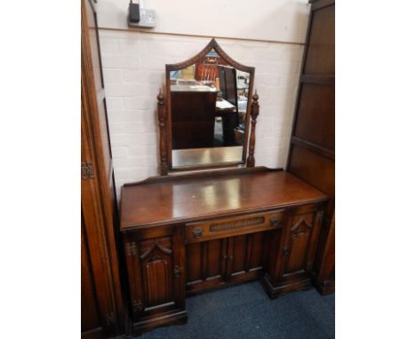 An Old Charm dressing table, with a single frieze drawer over cupboard doors, flanked by linenfold panelled doors, raised on 