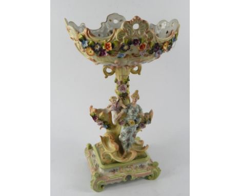 A German porcelain late 19thC comport, the rococo oval shaped bowl encrusted with flowers, raised on a triple vase trunk stem