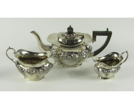 An Edwardian silver three piece tea set, comprising teapot, sugar basin and milk jug, of fluted oval design and with repoussé