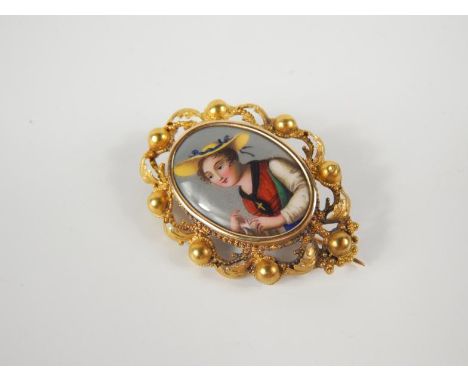 A 19thC oval painted enamel portrait brooch, of a Swiss girl with broad brimmed hat, within a yellow metal pierced mount havi