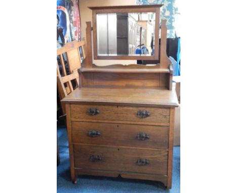 An Art Nouveau oak dressing chest, the swing frame mirror above a serpentine shelf, over three only graduated drawers, raised