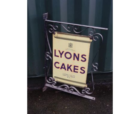 A Lyons Cakes enamel advertising sign, in a scrolling block cast iron wall mounting frame, sign 38cm x 55cm.