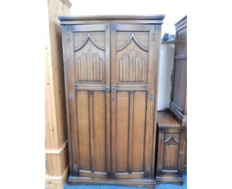 An Old Charm oak gentleman's wardrobe, with a pair of linenfold panelled doors opening to reveal hanging space, glazed compar