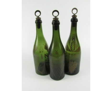 Three early 19thC green glass bottles for Brandy, Whisky and Gin, each with over painted decoration, matching named stoppers,